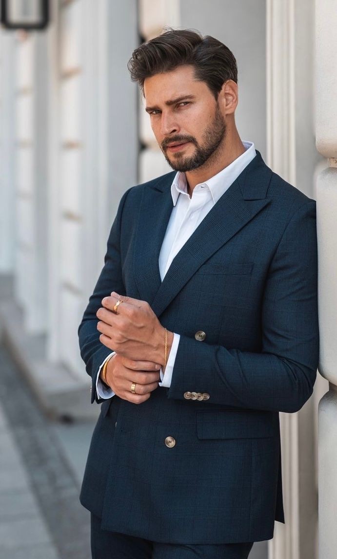 Man in a blue suit standing outside a building, looking confidently at the camera.